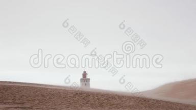 在沙尘暴中缓慢运动的大沙丘后面的远离RubjergKnude海滩灯塔的大气背景视图。